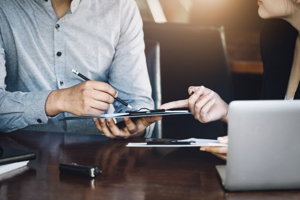 团队合作理念，咨询，男经济学家拿着笔指着预算，财务和投资文件，与女顾问在会议室讨论和规划财务。图片下载