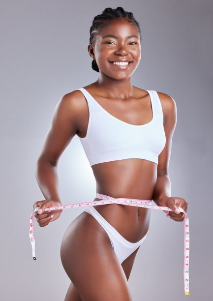 这张照片拍摄的是一名年轻女子在工作室背景下用卷尺测量自己的腰围图片下载