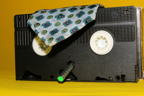 头戴复古领带的老式录像带，嘴里叼着蜡笔的创意概念磁带图片下载