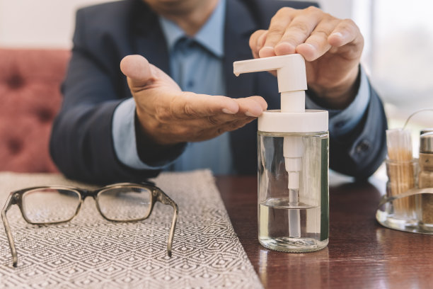 一名商人在午餐前用洗手液清洗双手上的细菌。冠状病毒的消毒。图片下载