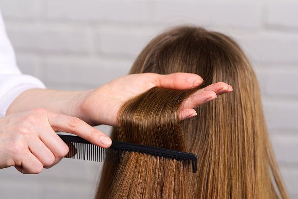 女人头发护理。美发师在美容院为年轻女孩做发型。图片下载