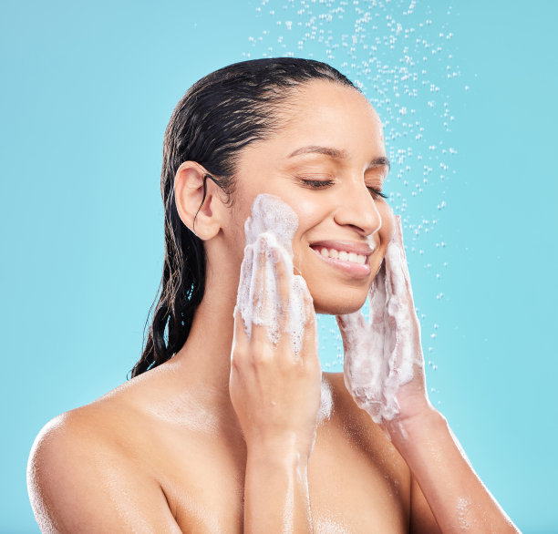 一名年轻女子在蓝色背景下洗脸的照片图片下载