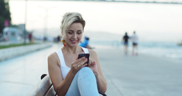 在公园里用智能手机写信息的女人。图片下载