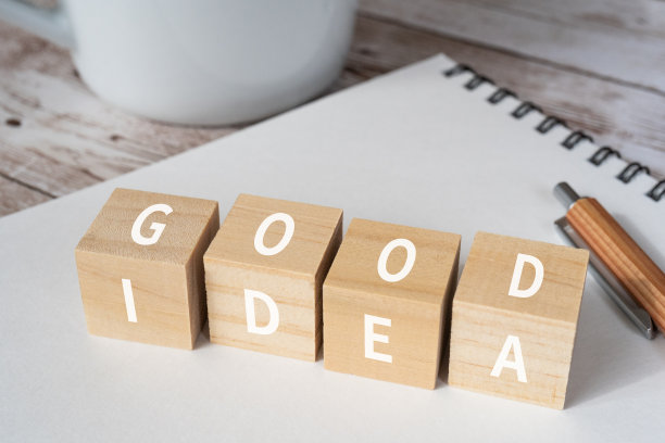 木块上有“GOOD”和“IDEA”的概念文本，一支笔，一个笔记本，和一个杯子。图片下载