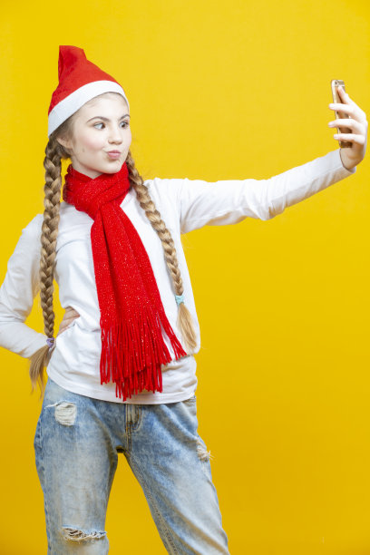 迷人的年轻白人女性女孩在圣诞帽自拍图片下载