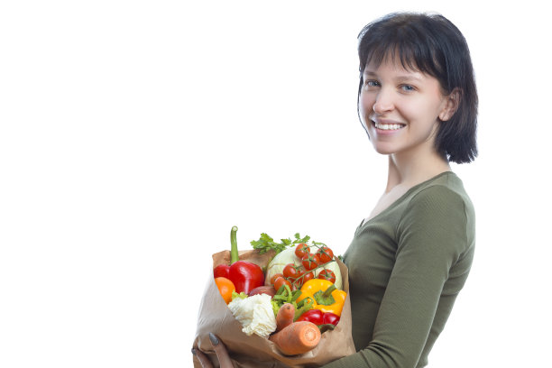 健康饮食的概念。微笑的白人黑发女孩拿着生态纸袋蔬菜和杂货在休闲服装反对白色。图片下载