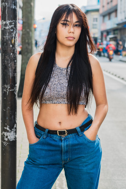 美丽的拉丁女孩与棕色皮肤摆非常严肃的相机，并集中在照片拍摄。等待交通工具的大学生。时尚的概念。图片下载