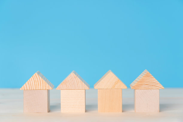 在蓝色的背景上，有四座由玩具木头立方体组成的房子图片下载