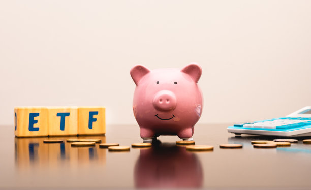 一个储蓄罐，最初的ETF是用英文写在木块上的“交易所交易基金”一词。在图像组合中有计算器和硬币。投资和经济概念。图片下载