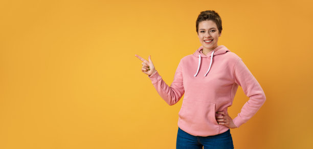 年轻女子短发在工作室的颜色背景指着手指的一边图片下载