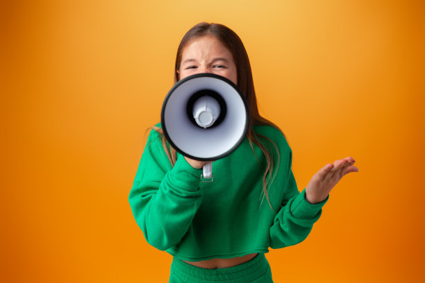 在橙色背景下用扩音器做通知的少女图片下载