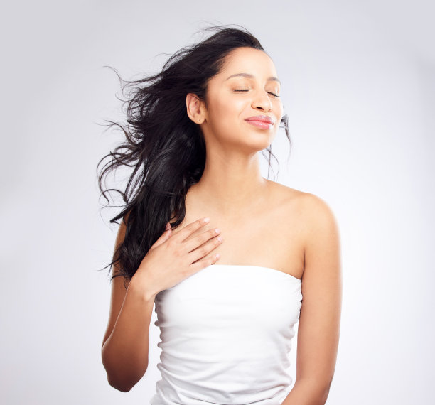 这张照片拍摄的是一名年轻女子，在白色的背景下摆姿势，头发看起来很健康图片下载