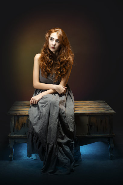 穿着连衣裙的年轻女孩盘腿坐在咖啡桌上，目光移开，带着若有所思和担忧的表情。图片下载