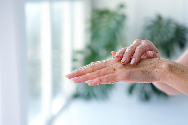 特写的女人是手与咖啡按摩磨砂在怪物模糊的背景。美容、手部护理、spa化妆品、美容理念。图片下载