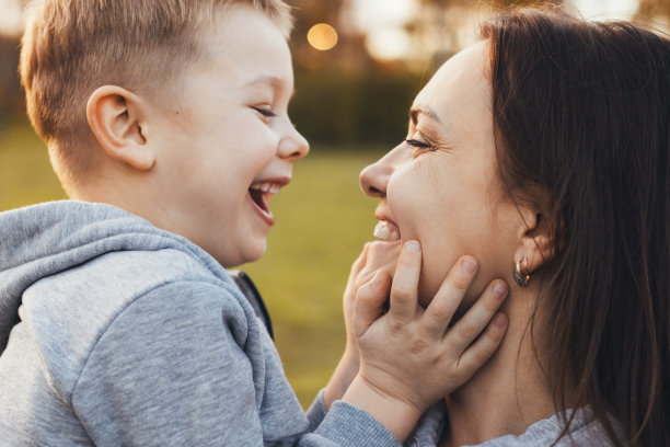 一个快乐的母亲抱着她的孩子在户外的自然的侧面照片。肖像生活方式设计。家庭日。户外的乐趣。图片下载