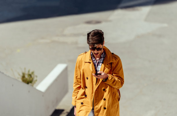 穿着黄色外套的年轻经理在用手机图片下载