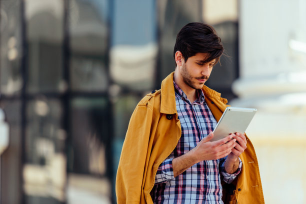 身着黄色外套的城市律师在市中心使用平板电脑图片下载