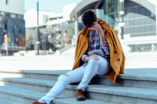 穿着外套的商人在城市里坐着用平板电脑图片下载