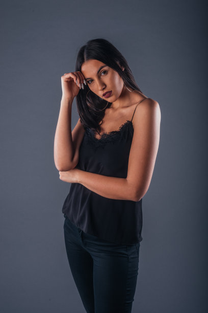 性感的工作室肖像的一个性感的女人站在一个灰色的背景与一只手臂交叉图片下载