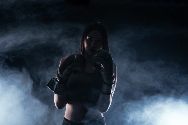 一个戴着拳击手套的女模特的剪影肖像，背景是白烟图片下载