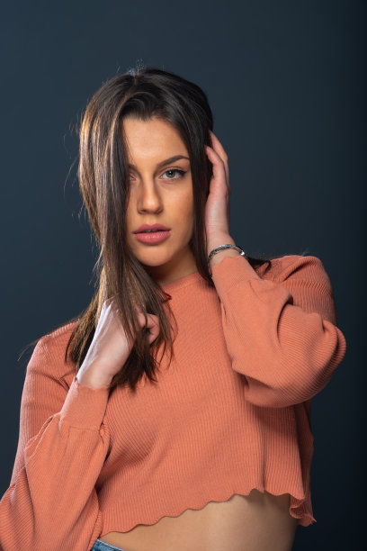 漂亮的年轻女性模特的近距离肖像与黑色背景上的橙色衬衫图片下载