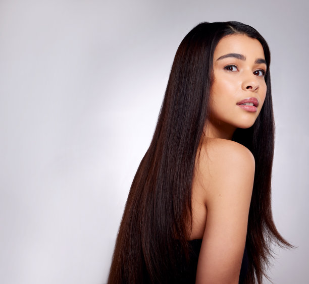 一个迷人的年轻女子在灰色背景下摆姿势的工作室肖像图片下载