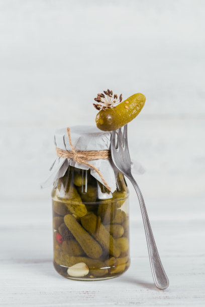 自制的罐头。白色木桌上放着玻璃罐里的腌黄瓜、莳萝和大蒜。冬天的蔬菜沙拉。图片下载