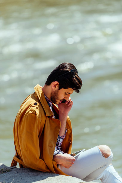 穿着外套的商人在城市里坐着用平板电脑图片下载