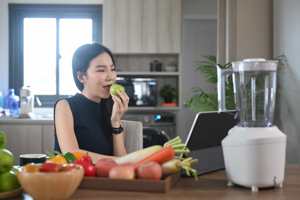 在厨房做健康的冰沙之前，亚洲妇女搜索烹饪菜单和准备材料。图片下载