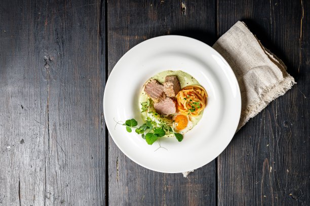 煎火鸡肉牛排，单面煎蛋，意大利面，香蒜沙司和蔬菜沙拉放在白色盘子里。热菜由肉禽制成。美味的食物。黑色木制背景。前视图。本空间图片下载