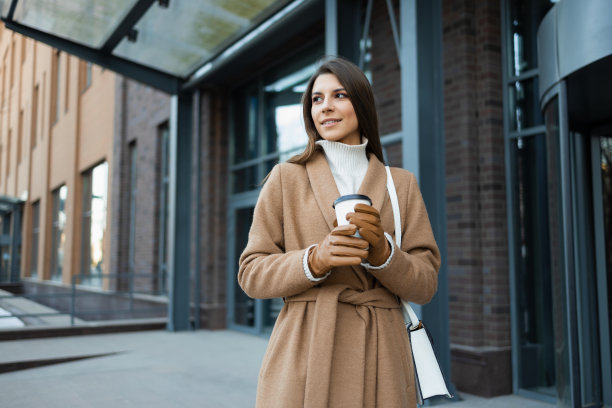 拿着咖啡杯的女子在商业中心大楼的背景上图片下载