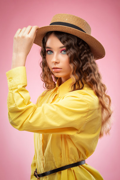 活泼的小女孩，一头卷发，漂亮的妆容，黄色的裙子，一顶草帽。图片下载