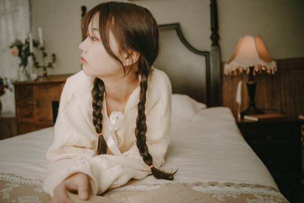 一个美丽的亚洲女孩在床上看书图片下载