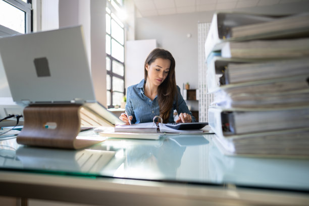 年轻的女商人在办公室工作与成堆的文件夹图片下载