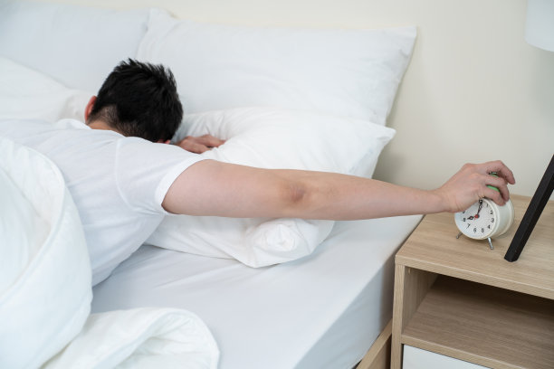 亚洲有魅力的年轻人关掉早上的闹钟。帅男觉得懒，累了躺在舒适的床上，在卧室里无视噪音，继续睡觉不想醒来图片下载