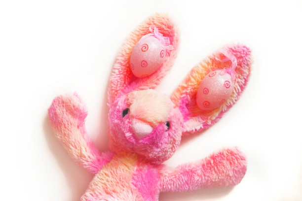 可爱的软兔子玩具在白色的背景。复活节带蛋的粉色兔子图片下载