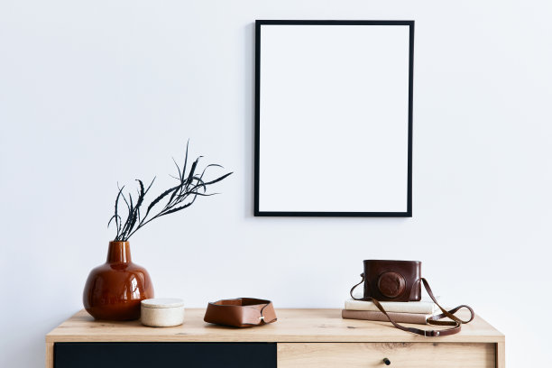 时尚的室内客厅与模拟海报框架，木制马桶，书，叶片在陶瓷花瓶，照片相机和优雅的个人配件。家居装饰的极简概念。模板。图片下载
