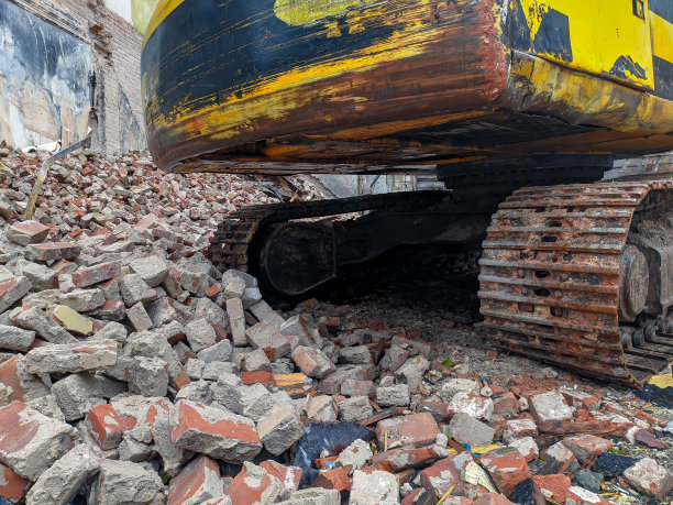 挖土机把墙上的一堆堆砖给毁了。旧建筑的破坏。图片下载