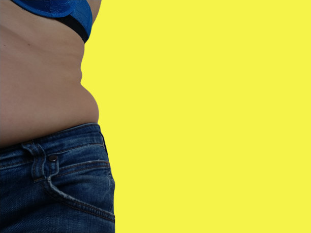 下垂的腹部。两边的皮革和脂肪的皱褶垂在牛仔裤的腰部。因暴饮暴食或怀孕而宠坏的人。肥胖和糖尿病。不健康的生活方式。脂肪团松弛的肌肉图片下载