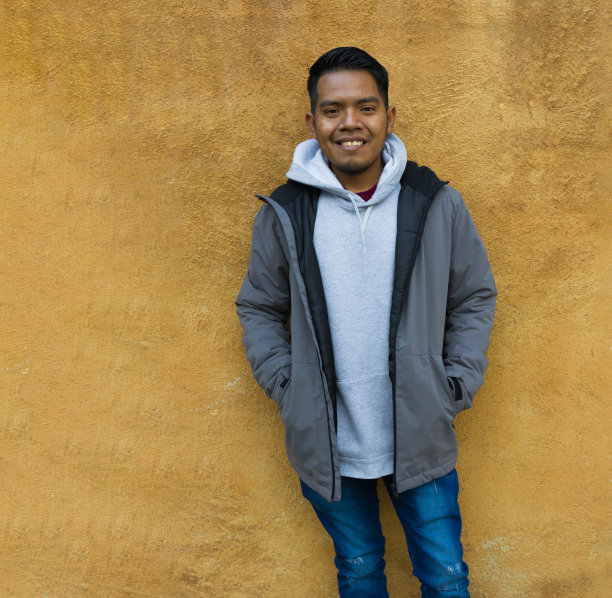 一个墨西哥种族的动画男子站在一堵黄色的墙前微笑。图片下载