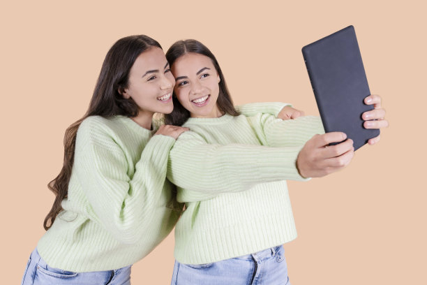 两名西班牙裔双胞胎姐妹用平板电脑自拍图片下载