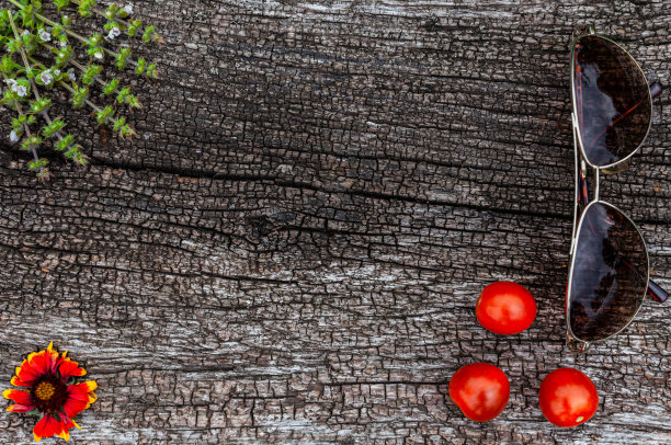 自然木制表面上躺着一朵花，番茄，太阳镜图片下载