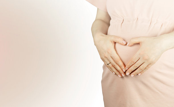 孕妇将手放在肚子上，用爱心表示爱。图片下载