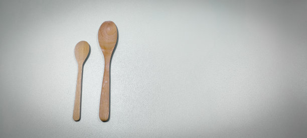 两个不同大小的木勺在灰色的背景上。图片下载