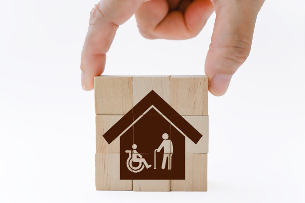 手握房子与老人和残疾人的图标堆栈木立方体，孤立的背景为家庭照顾老年人的概念图片下载
