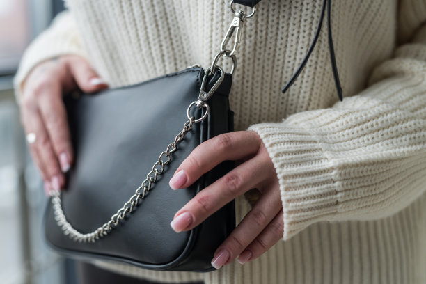 经验丰富的女孩模特广告一个奇妙的时尚优雅的包在她的手中。图片下载