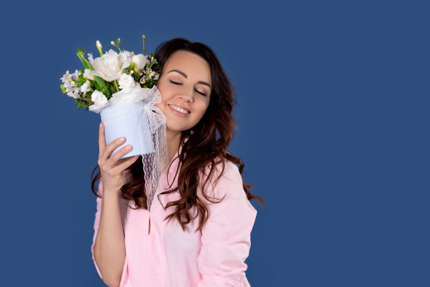 度假与美容理念。女性化的女人收到花，拿着美丽的花束，开心地笑着，蓝色的背景图片下载