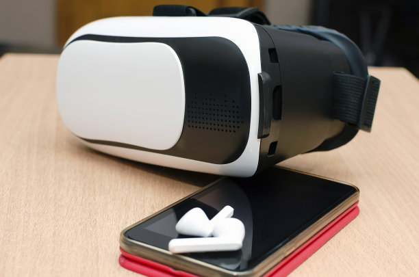 桌上放着虚拟现实眼镜、智能手机和耳机。虚拟游戏和视频观看配件。现代技术的概念。图片下载
