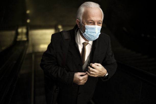 高级商人在自动扶梯上戴着防护口罩图片下载