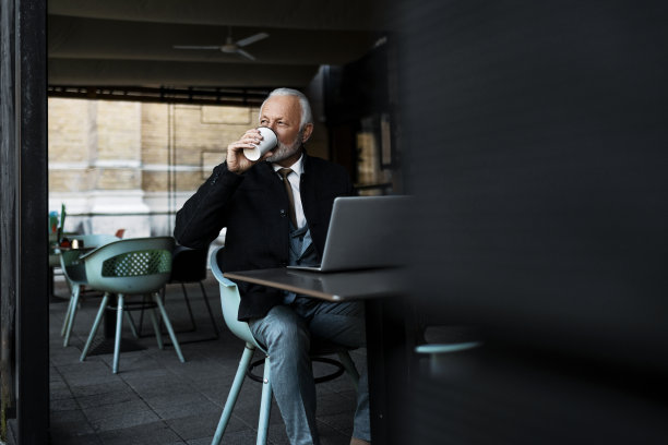 资深商人在喝咖啡休息时使用笔记本电脑图片下载